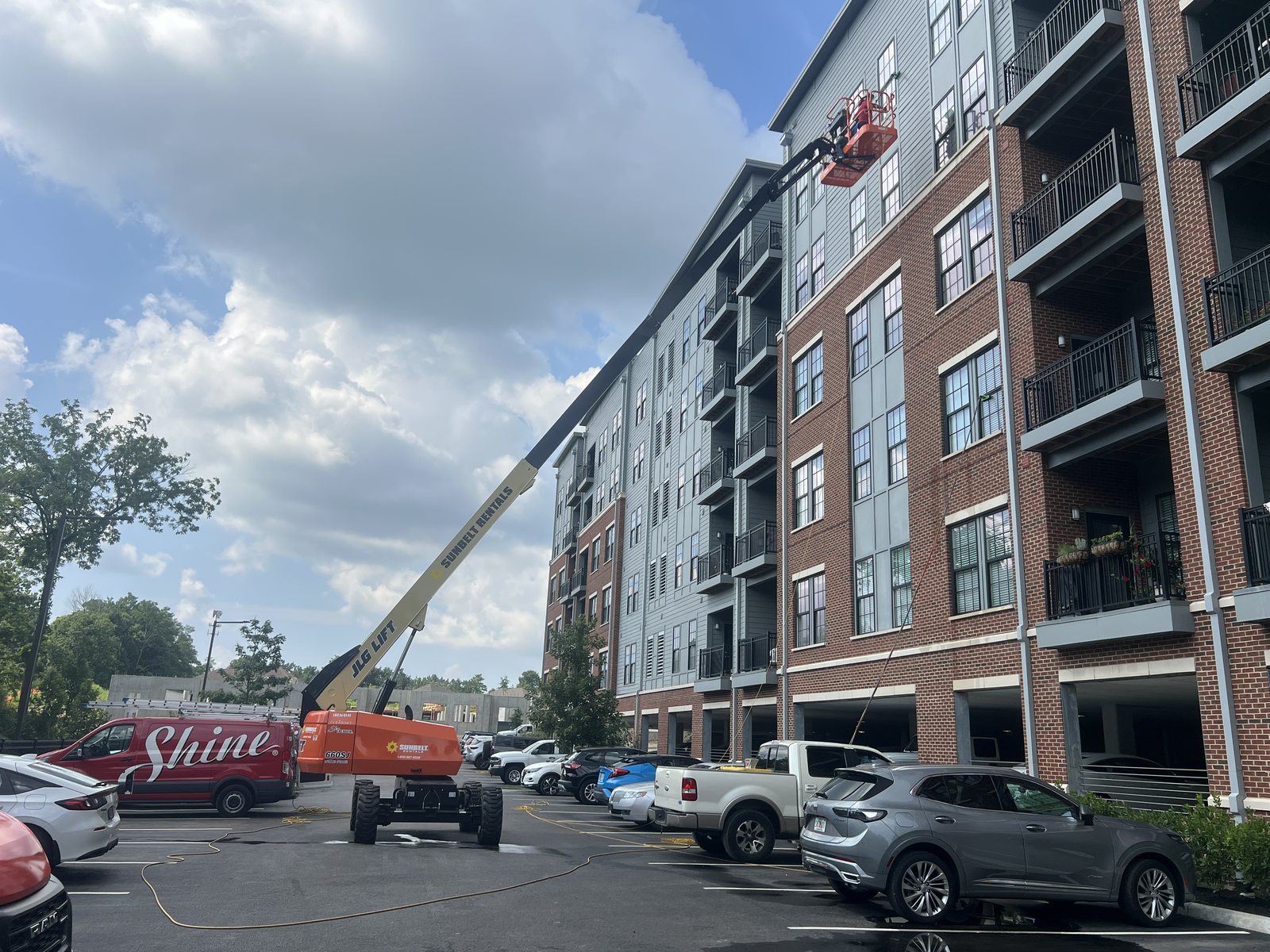 Boom lift work on upper-floor glass at a five-story multi-family property — commercial window cleaning by Shine