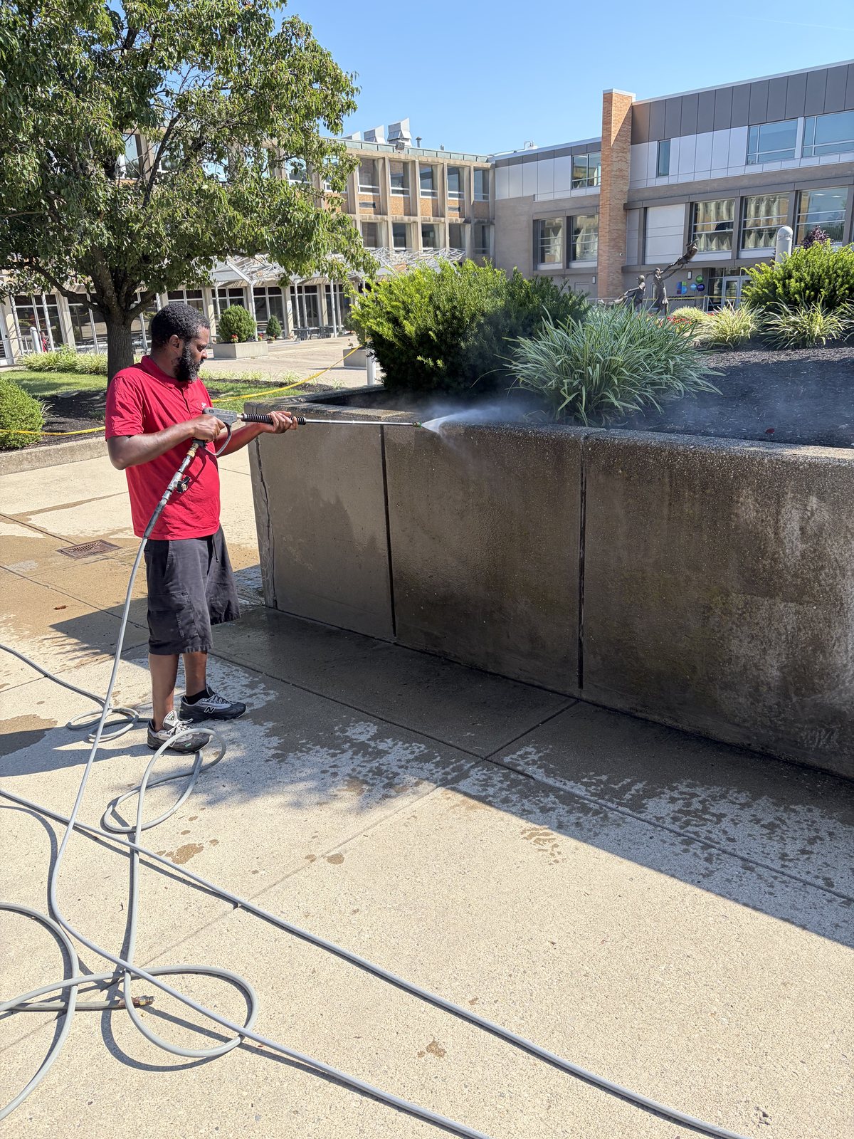 Technician cleaning hardscape and masonry on an institutional campus