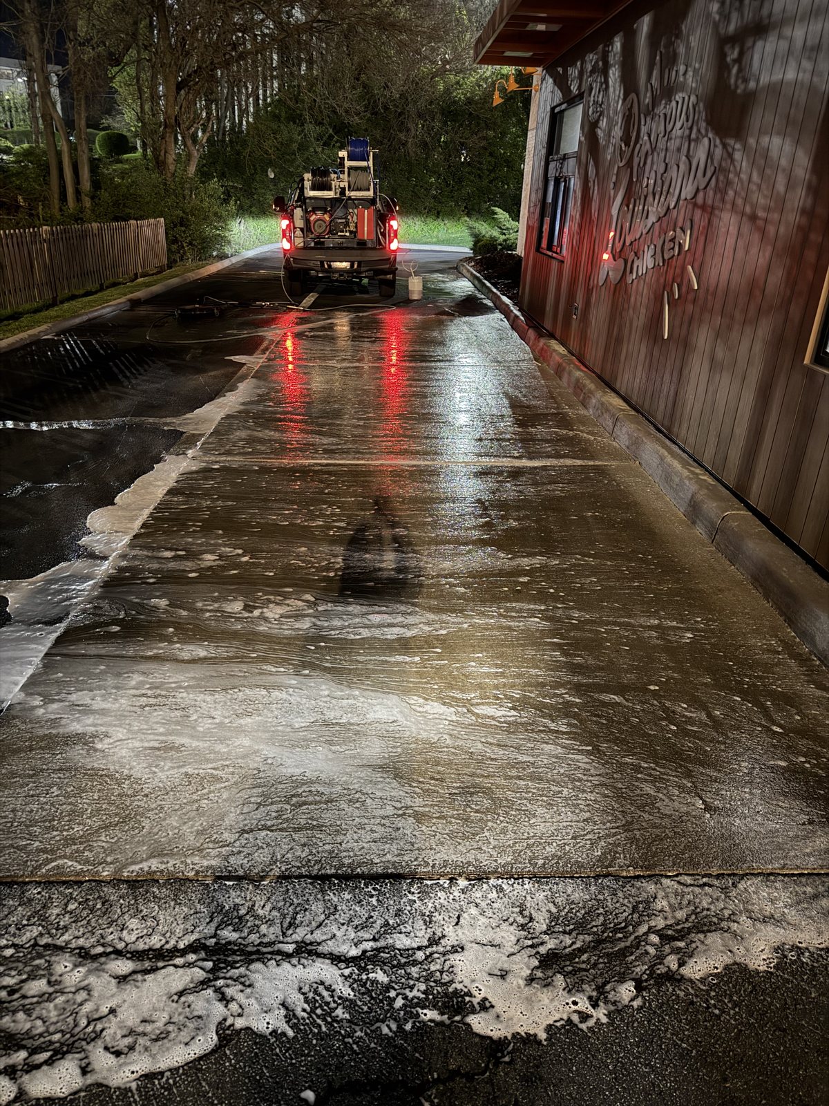 Technician cleaning a quick-service restaurant drive-thru and lot overnight