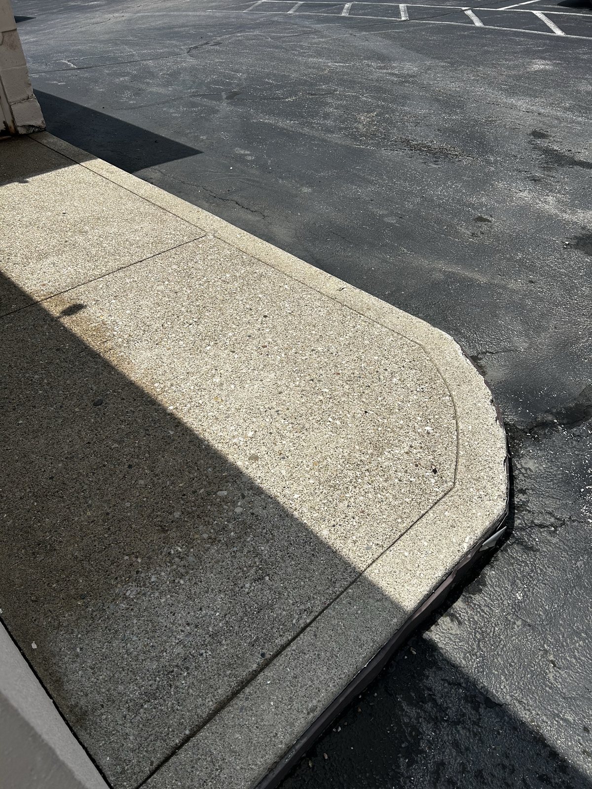 After — Concrete sidewalk and curb line at a retail property, flat surface pressure washing by Shine