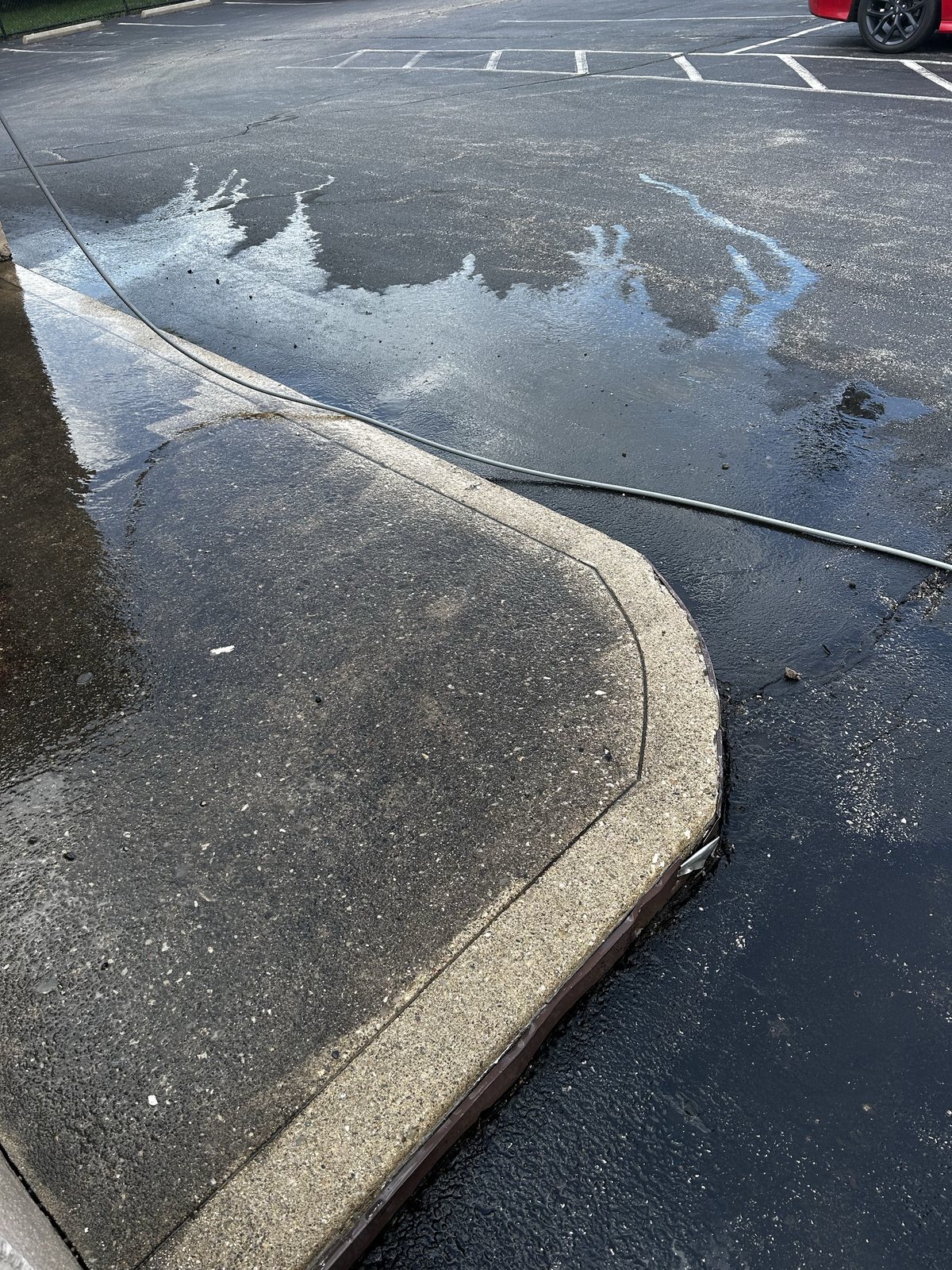 Before — Concrete sidewalk and curb line at a retail property, flat surface pressure washing by Shine
